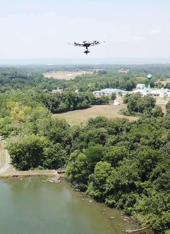 A civilian drone collecting hyperspectral survey data above a reservoir and trees in West Virginia.