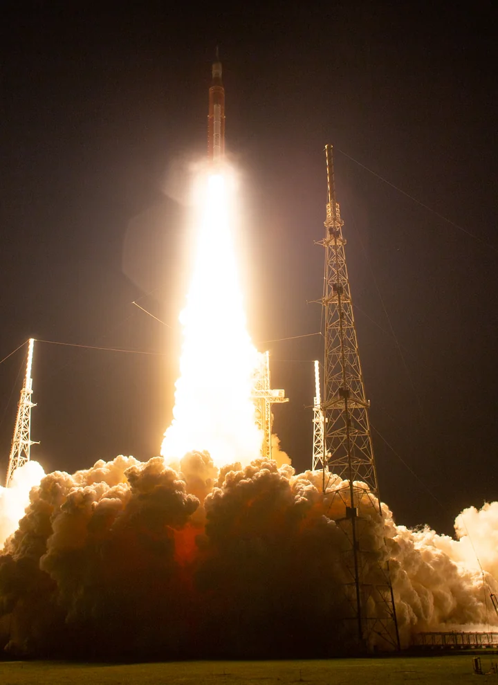 NASA Artemis I launching from Kennedy Space Center at night, with an illuminated exhaust plume.